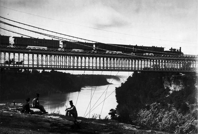 Puente sobre el Niágara, donde se aprecian los tirantes bajo el tablero. Locomotoras a vapor, carruajes, señores con bastón y chistera… el sabor del siglo XIX, en definitiva