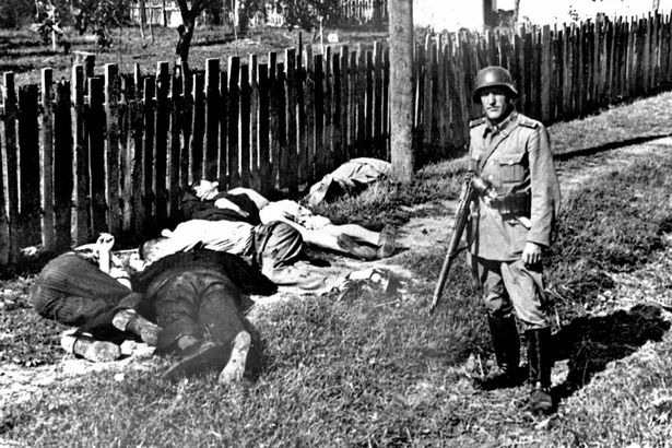 Soldado alemán posa junto a civiles yugoslavos muertos (PD).