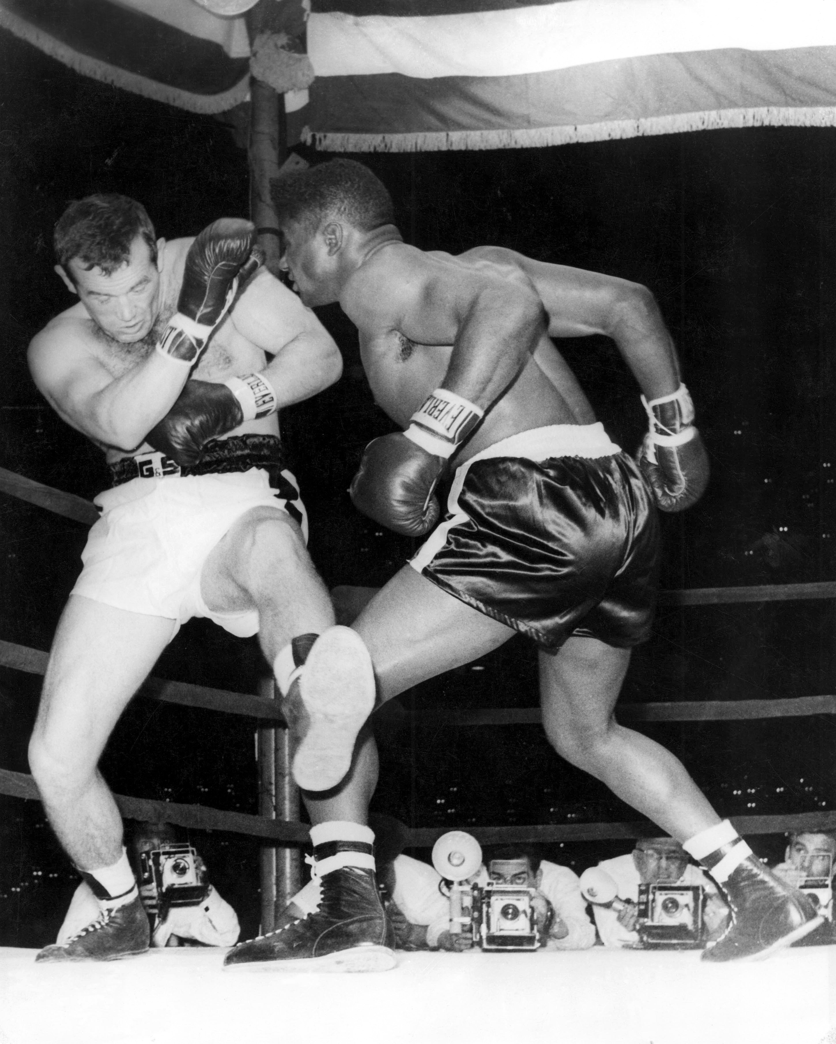 By knocking out world heavyweight boxing champion, Swedish Ingemar Johansson, in the fifth round of their title fight in New York, 25-year-old Floyd Patterson, made history as the only heavyweight champion of the world to regain his lost title. The fight was a complete reversal of the contest last June when Johansson, then the challenger, finished the fight and claimed the title in three rounds. Picture shows Johansson, forced against the ropes by Patterson's pushes, uses weird, unorthodox footwork, as he tries in vain to move away. 23rd June 1960