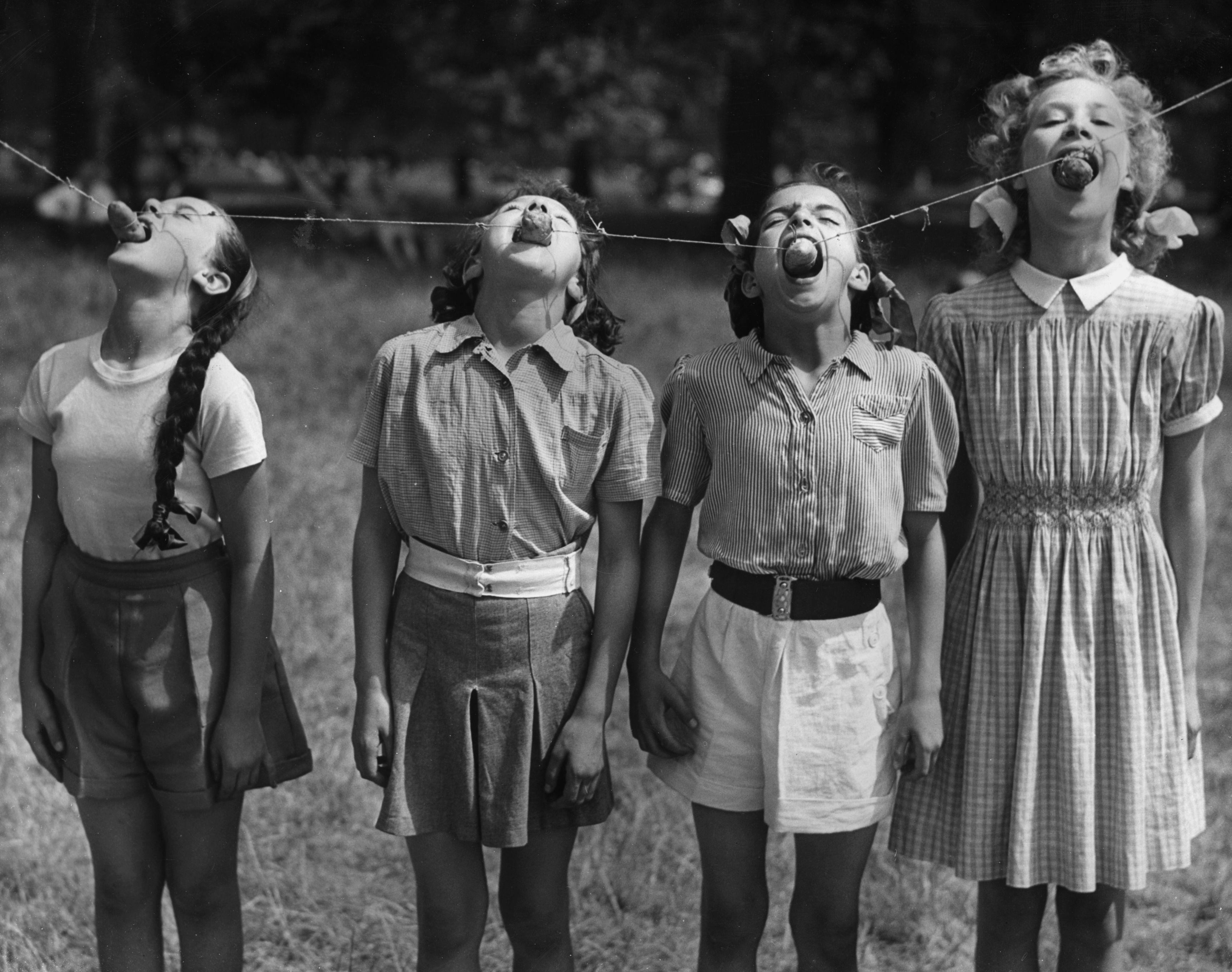 25th July 1952: Four young dancers of the Italia Conti School compete in a potato eating contest in Green Park, London. They are (L to R) Frances Reynolds of Palmers Green, Sonia Hoey of Hampton Court, Maureen Bullion of Catford and Elizabeth Hewitt of Erith in Kent. (Photo by Reg Speller/Keystone/Getty Images)