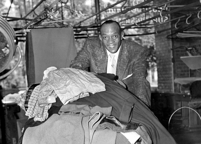 Jesse Owens who runs a dry cleaning business in Chicago seen pushing a truck. 1st July 1954