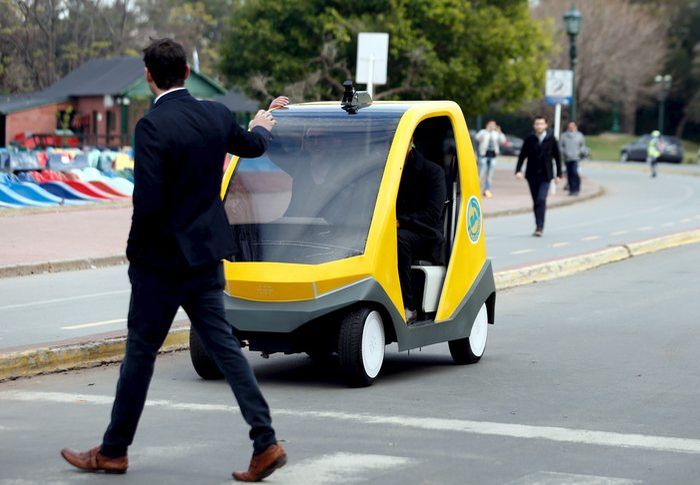 A man crosses the street as a prototype of an autonomous electric vehicle stops during its presentation in Buenos Aires, August 19, 2015. The autonomous vehicle, the first of its kind developed in Argentina, is able to fulfill the main functions of mobility of a traditional car but autonomously through the use of artificial intelligence that enables it to detect their surroundings and move without human intervention. REUTERS/Marcos BrindicciCODE: X90087