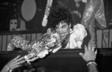 Minneapolis, Minnesota, USA --- Prince crawls toward front of stage and recieves flowers from fan, --- Image by © Mark Downey/Lucid Images/Corbis