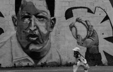A boy plays baseball near a mural of Venezuela's late president Hugo Chavez, in Caracas, Venezuela September 8, 2016. REUTERS/Henry RomeroCODE: X90174