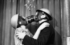 A couple kissing under the mistletoe, wearing gas masks.   (Photo by Fox Photos/Getty Images)