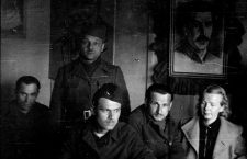 Gunvor Galtung Haavik og fire menn. Bilde av Stalin på veggen. Gunvor Galtung Haavik arbeidet som tolk for Leiv Kreyberg.