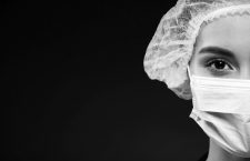 Cropped portrait of serious doctor in medical cap and mask isolated over black