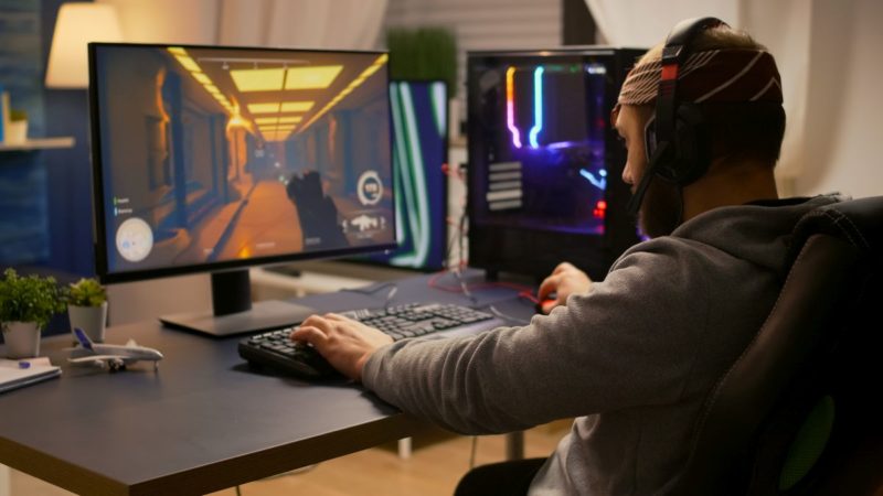 videogamer winning first person shooter tournament using rgb keyboard and professional headphones pro player man talking with other players online for game competition on powerful computer