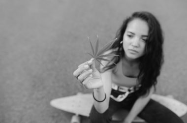 attractive girl sits logboard holds piece cannabislow