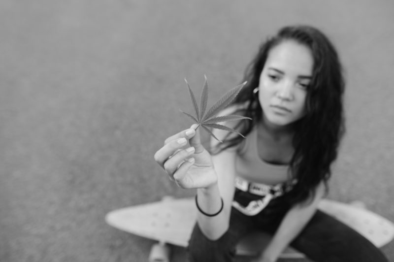 attractive girl sits logboard holds piece cannabislow