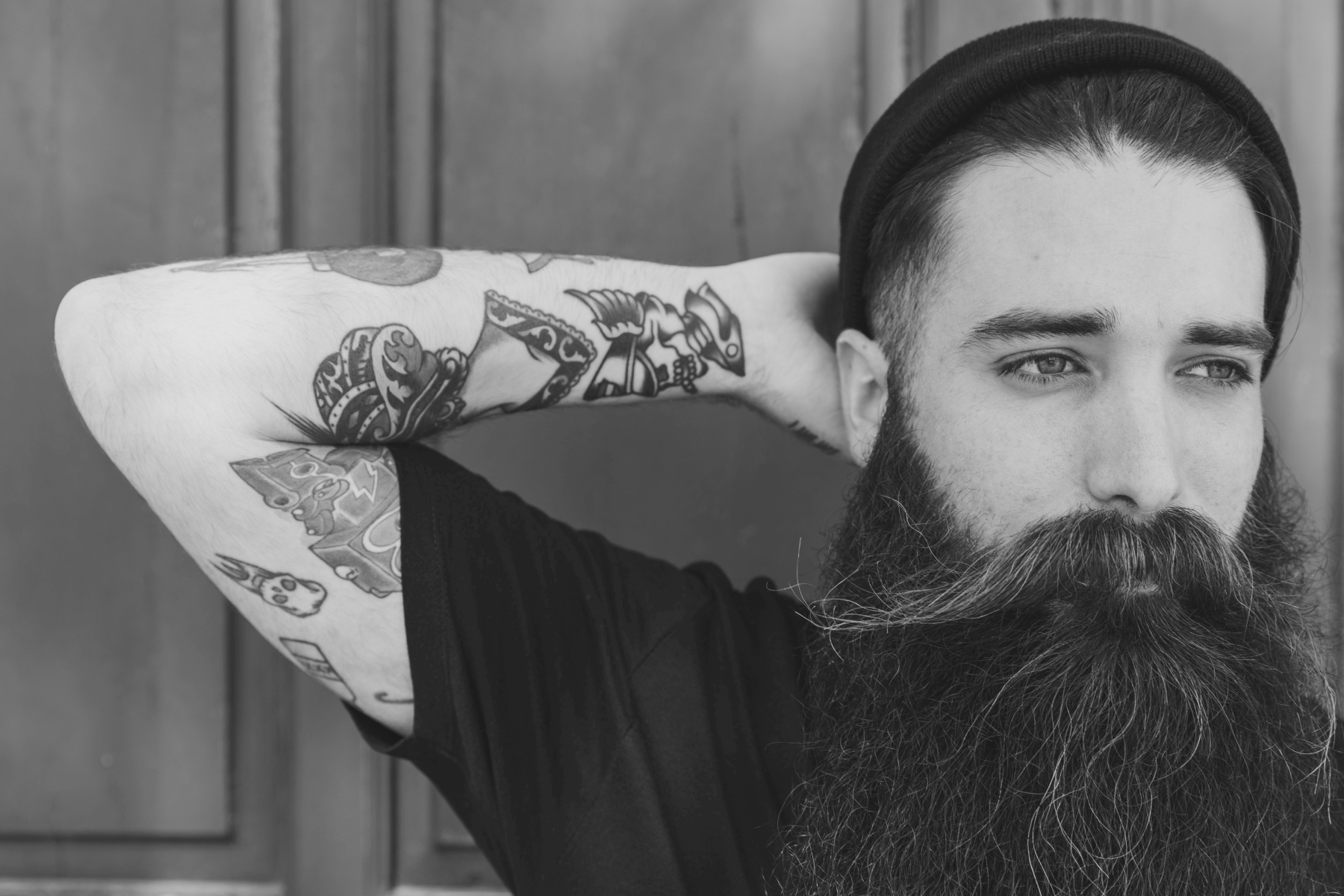 La decadencia del tatuaje occidental. Atlas de la tontería epidérmica. 1 portrait bearded young man with colorful tattoo his hand against red backdropbn